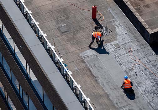 Arbeiter, der mit einer Kelle Mörtel auf die Styroporisolierung und das Netz aufträgt