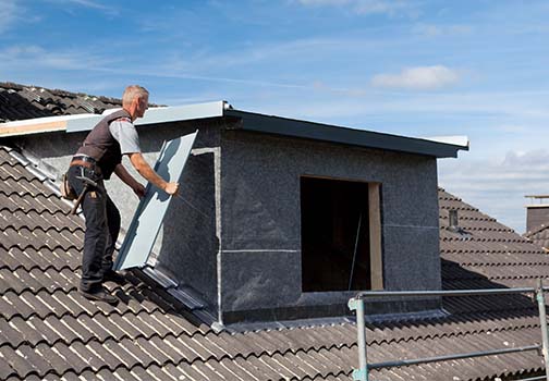 Arbeiter, der mit einer Kelle Mörtel auf die Styroporisolierung und das Netz aufträgt